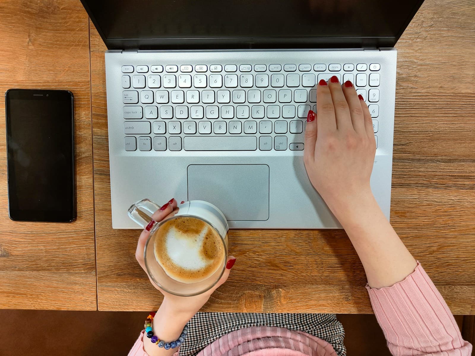Person typing on a laptop with a cup of coffee
