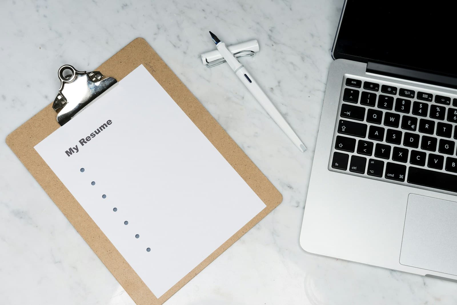 Resume document beside a silver laptop on a desk