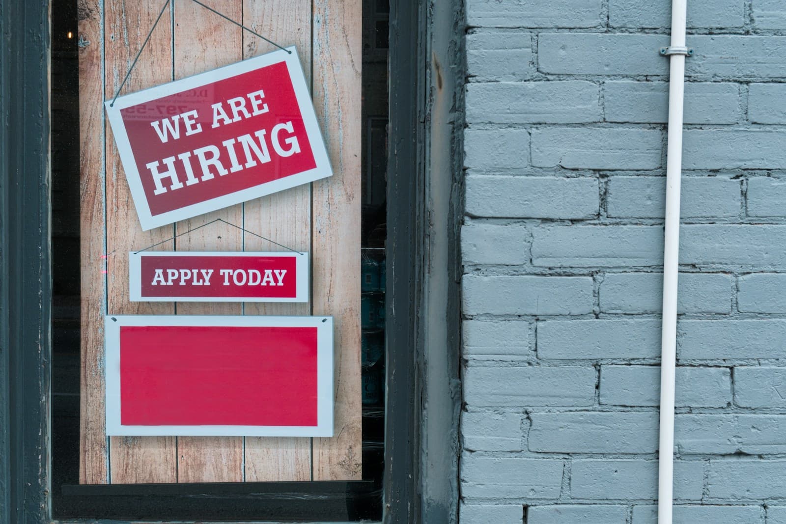 We are hiring sign displayed on a storefront